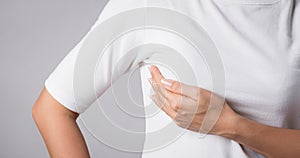 Woman hand checking lumps on her breast for signs of breast cancer on gray background. Healthcare concept