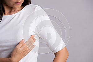 Woman hand checking lumps on her breast for signs of breast cancer on gray background. Healthcare concept photo