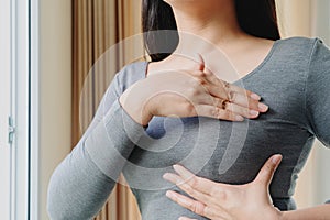 Woman hand checking lumps on her breast for signs of breast cancer. Women healthcare concept