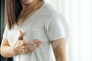 Woman hand checking lumps on her breast for signs of breast cancer. Women healthcare concept