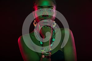 Woman With Hand On Chin Wearing Jewelry Over Black Background