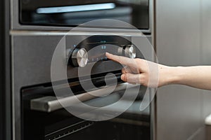 Woman hand choose program on electronic control panel built-in oven