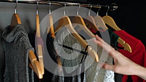 Woman hand choosing dress in wardrobe for evening dinner or party.