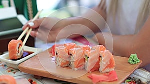 Woman Hand With Chopsticks Dipping Sushi Roll into Soy Sauce