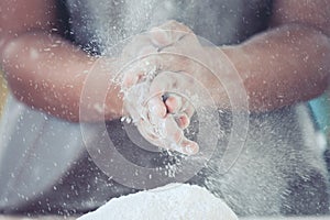 Woman hand clapping and sprinkling white flour on dough