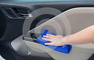 Woman hand cleaning interior car door panel with microfiber clot