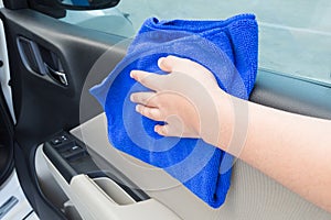 Woman hand cleaning interior car door panel with microfiber clot