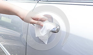 Woman hand cleaning removing germs with antibacterial wet wipes on car door handle for corona virus COVID-19