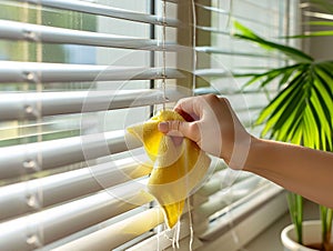 Woman hand cleaning window blinds with rag indoors photo