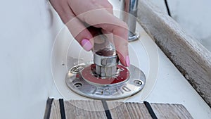 Woman hand closing the fuel tank cap on a moored yacht after refueling