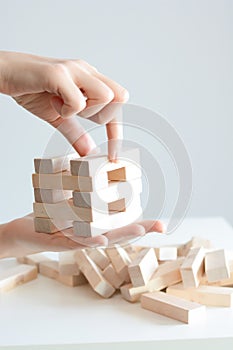 Woman hand constructing a tower of wooden blocks on a white background