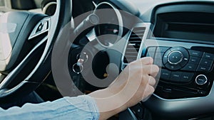 Woman hand control radio or music in car in motion