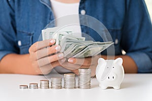 Woman hand counting America dollars banknotes money with stack of coins and piggy bank. Saving money wealth and financial