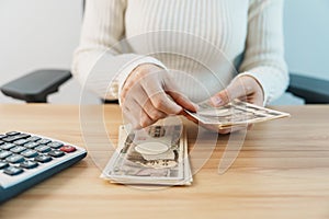 Woman hand counting Japanese Yen banknote with calculator. Thousand Yen money. Japan cash, Tax, Recession Economy, Inflation,