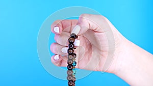 Woman hand counts mala beads strands used for keeping count during mantra meditations. Blue background. Spirituality