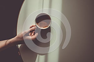 Woman hand with cup of americano or expresso on the white table. Morning coffee concept. Sunday loneliness relaxing