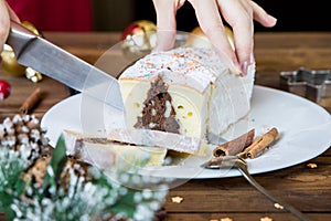 Woman hand cut christmas chocolate cake with holiday decoration. Food xmas background.