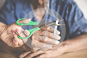 Woman hand cut cigarette of her father by scissors ,stop smoking concept