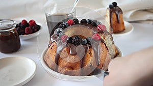 Woman hand cut a tasty homemade vanilla bunt cake with berries