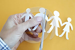 Woman hand cuts paper figures in form of family with scissors closeup