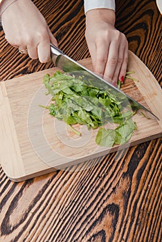 Woman hand cutting spinach using a sharped big kitchen knife