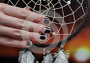 Woman hand with dark nail design.