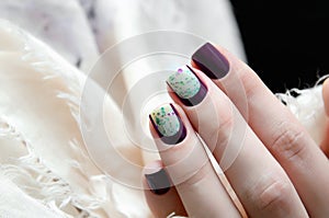 Woman hand with dark nail design.