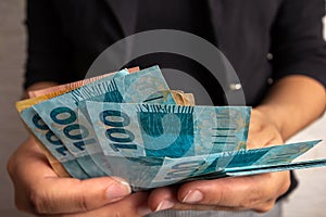 Woman hand dealing with money from Brazil.