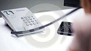 Woman hand dialing number on telephone at office