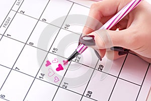 Woman hand drawing and paint heart in calendar with felt pen for Valentines day