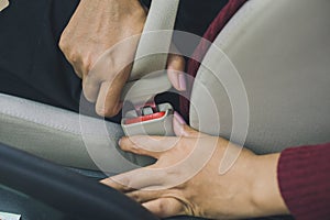 Woman hand fastening a seat belt before driving