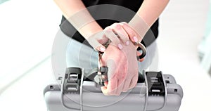 Woman hand fastens handcuffs holding suitcase with money