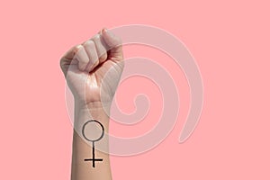 A woman hand and feminist sign tattoos on her hand isolate on pink background photo