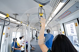 Woman hand firm grip safety handrail in elevated monorail train. Mass transit system in modern city. Inside of electric train.