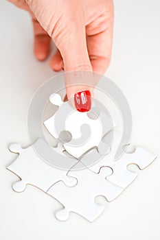 Woman hand fitting the right piece of puzzle suggesting business networking concept