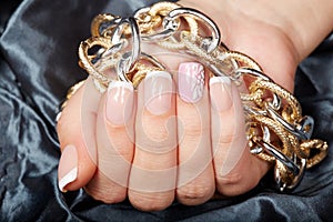 Woman hand with french manicured nails holding a chain necklace