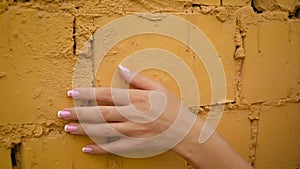 Woman hand gently stroke surface, slide on stony wall of old building .