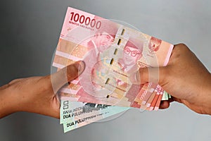 Woman Hand give Indonesian Money Rupiah. Woman hand is holding bunches of Indonesian Rupiah bank notes currency