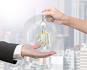 Woman hand giving key with house keyring to man hand