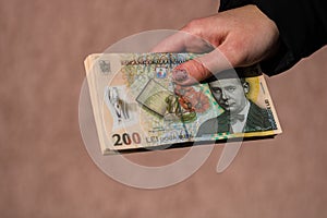 Woman hand giving money like bribe or tips isolated . LEI currency banknotes close up. Reward for hard work  finance and business