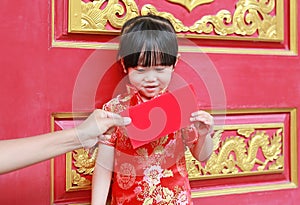 Woman hand giving red packet monetary gift for Cute little girl at chinese temple in bangkok, Thailand. Chinese new year concept