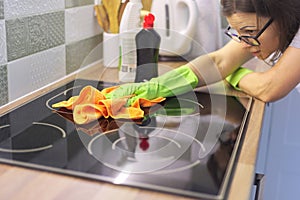 Woman hand in gloves cleaning kitchen electric ceramic hob