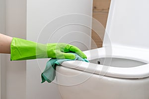 Woman hand in a green protection gloves cleaning toilet