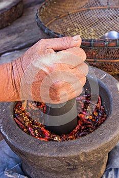 Woman hand is grinding chili and garlic by Granite mortar and pe