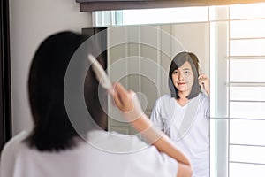 Woman hand having combing her hair in bedroom mirror