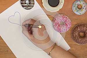 Woman hand, heart and donuts