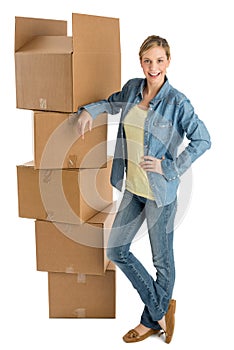 Woman With Hand On Hip Standing By Stacked Cardboard Boxes