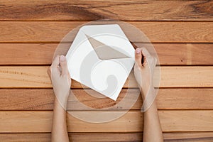 Woman hand hold a envelope and post card on the wood desk,