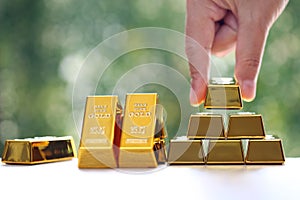 Woman hand hold the gold bar on natural green background, investment and business concept