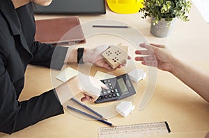 Woman hand hold a home model with calculate for housing loans. photo